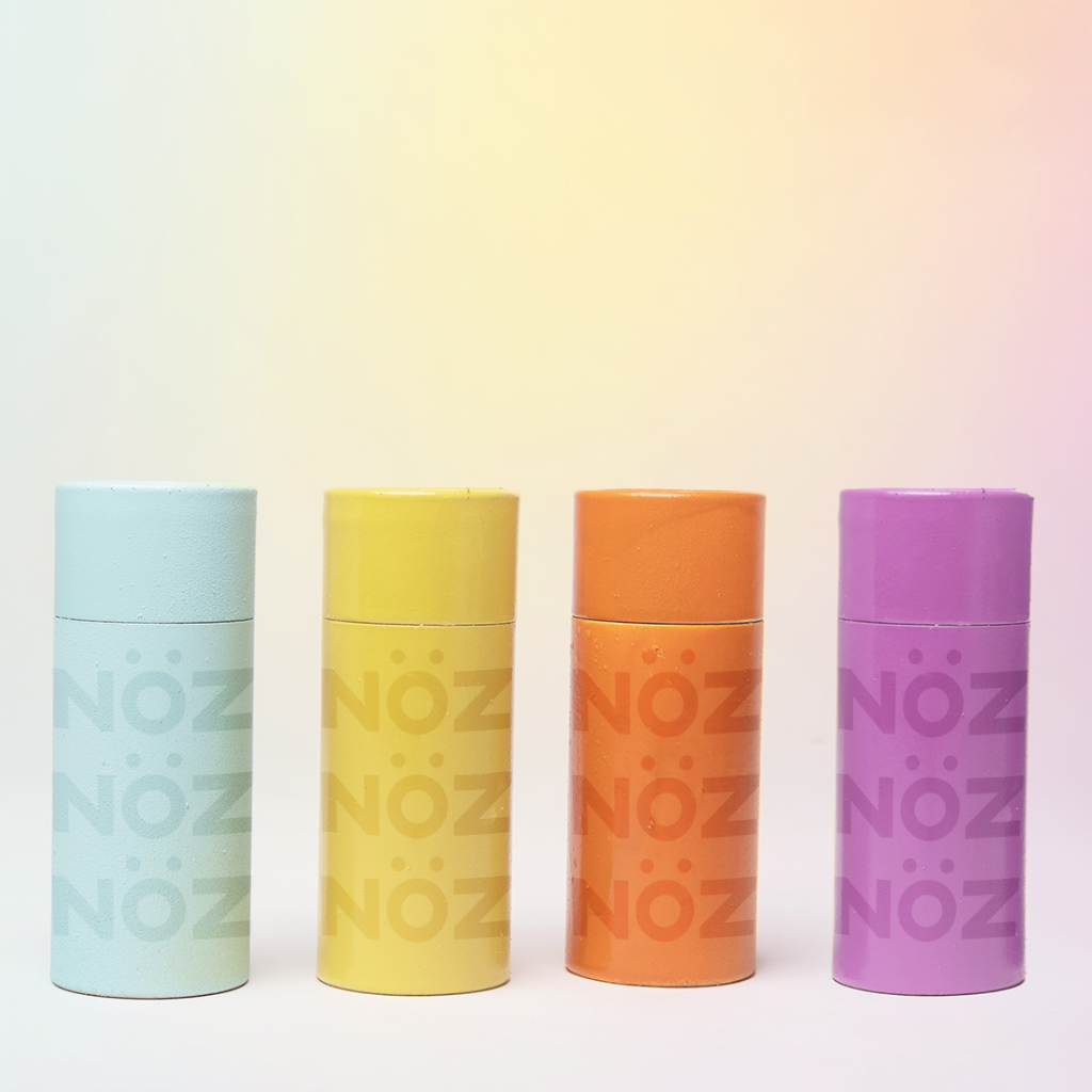 Line up of Nöz's different colors of SPF sunscreen. Blue, yellow, orange and purple